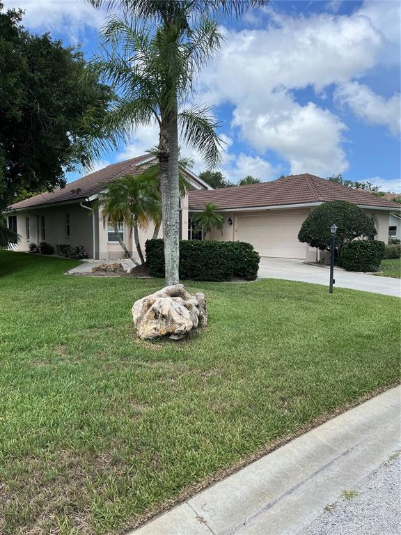 A single-story house with a tiled roof, a two-car garage, and a large front lawn — 174 GRAND OAK CIRCLE, VENICE, FL