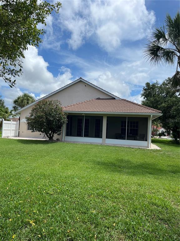 The exterior of a house features a screened-in patio and a large grassy backyard — 174 GRAND OAK CIRCLE, VENICE, FL