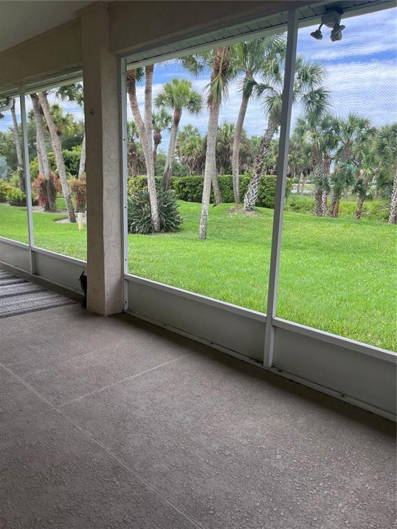A screened-in concrete patio overlooks a grassy lawn with palm trees and landscaping — 174 GRAND OAK CIRCLE, VENICE, FL