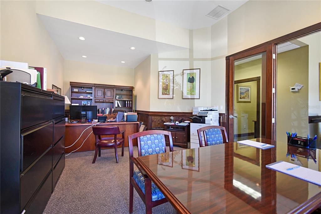 A professional office features a large wooden conference table, a desk, and dark cabinetry — 1301 PLANTATION ISLAND DRIVE S UNIT 303A, ST AUGUSTINE, FL