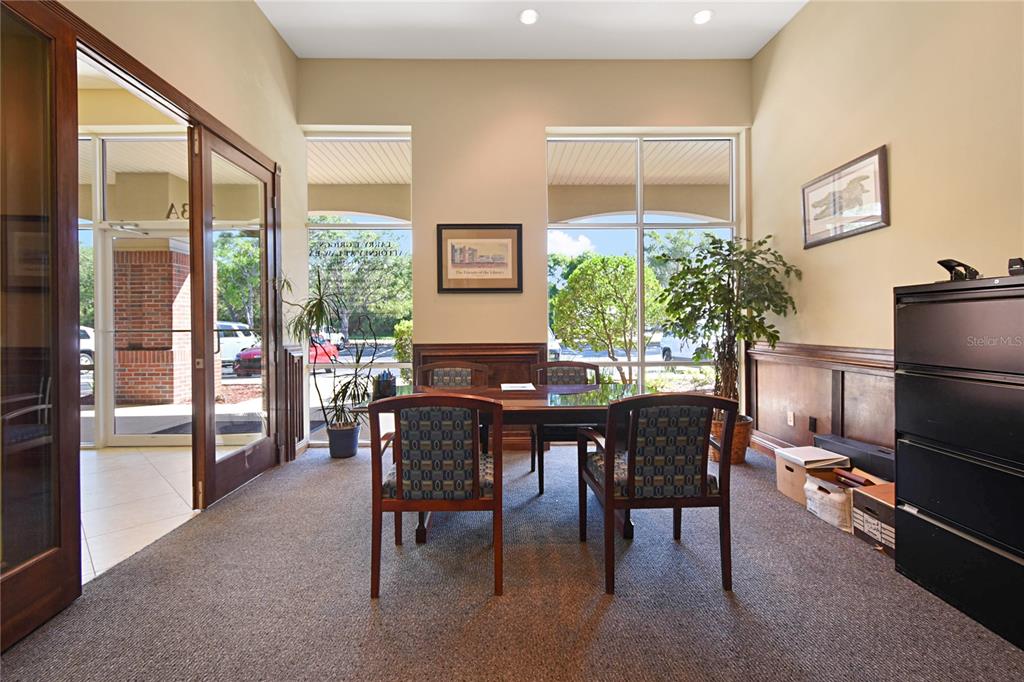 A small office features a wooden table, two patterned chairs, and large windows — 1301 PLANTATION ISLAND DRIVE S UNIT 303A, ST AUGUSTINE, FL