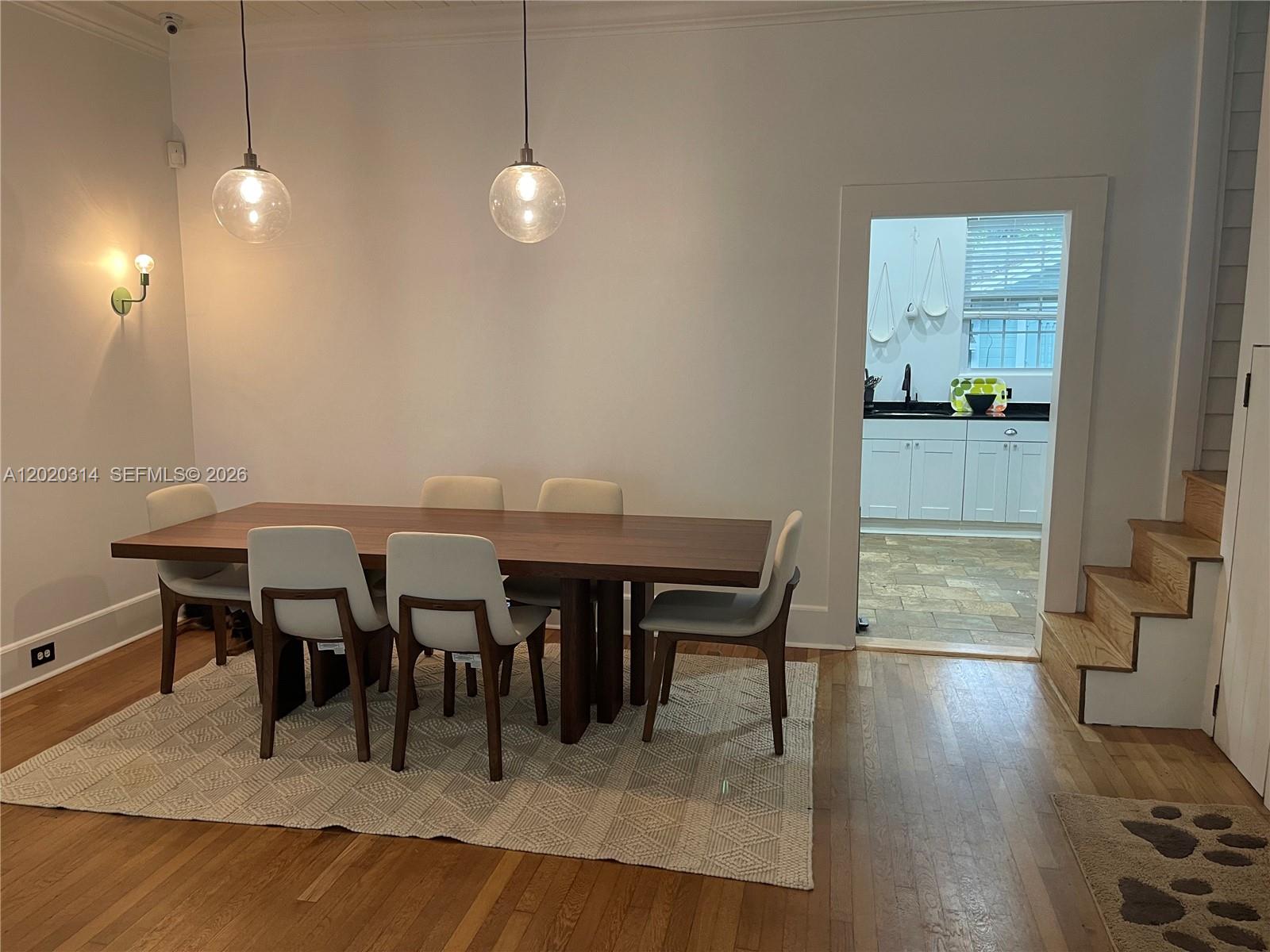 A dining room features a wooden table, six chairs, pendant lights, and a kitchen doorway — 27 NE 49th St, Miami FL 33137, MIAMI, FL