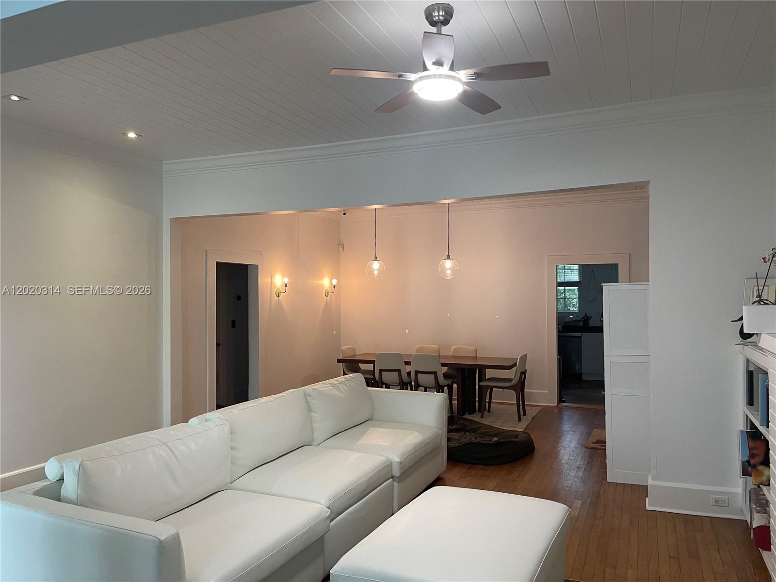 A living room with a white sectional sofa opens into a dining area with pendant lights — 27 NE 49th St, Miami FL 33137, MIAMI, FL
