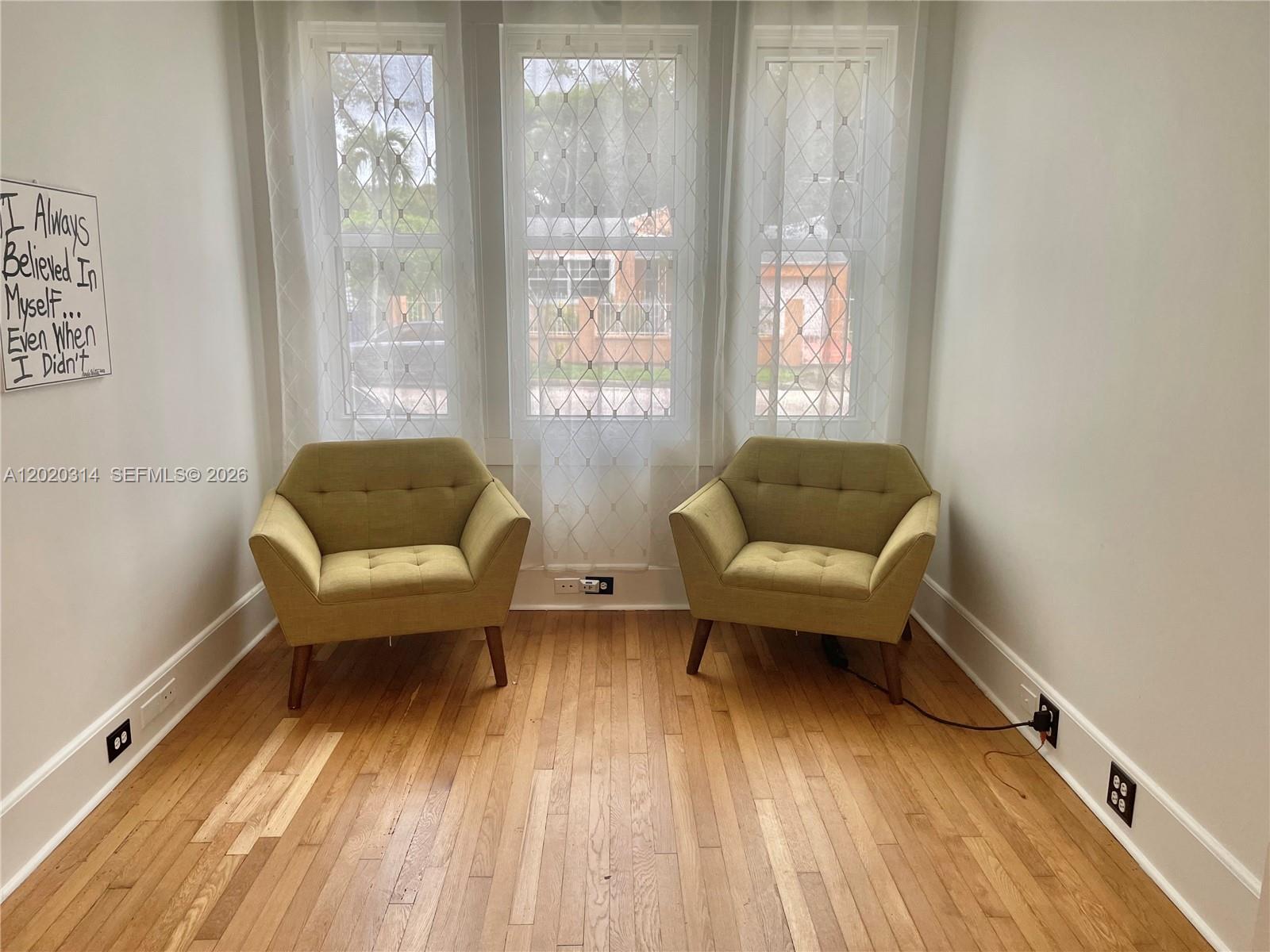 A room with hardwood floors, white walls, and two lime green armchairs facing a window — 27 NE 49th St, Miami FL 33137, MIAMI, FL