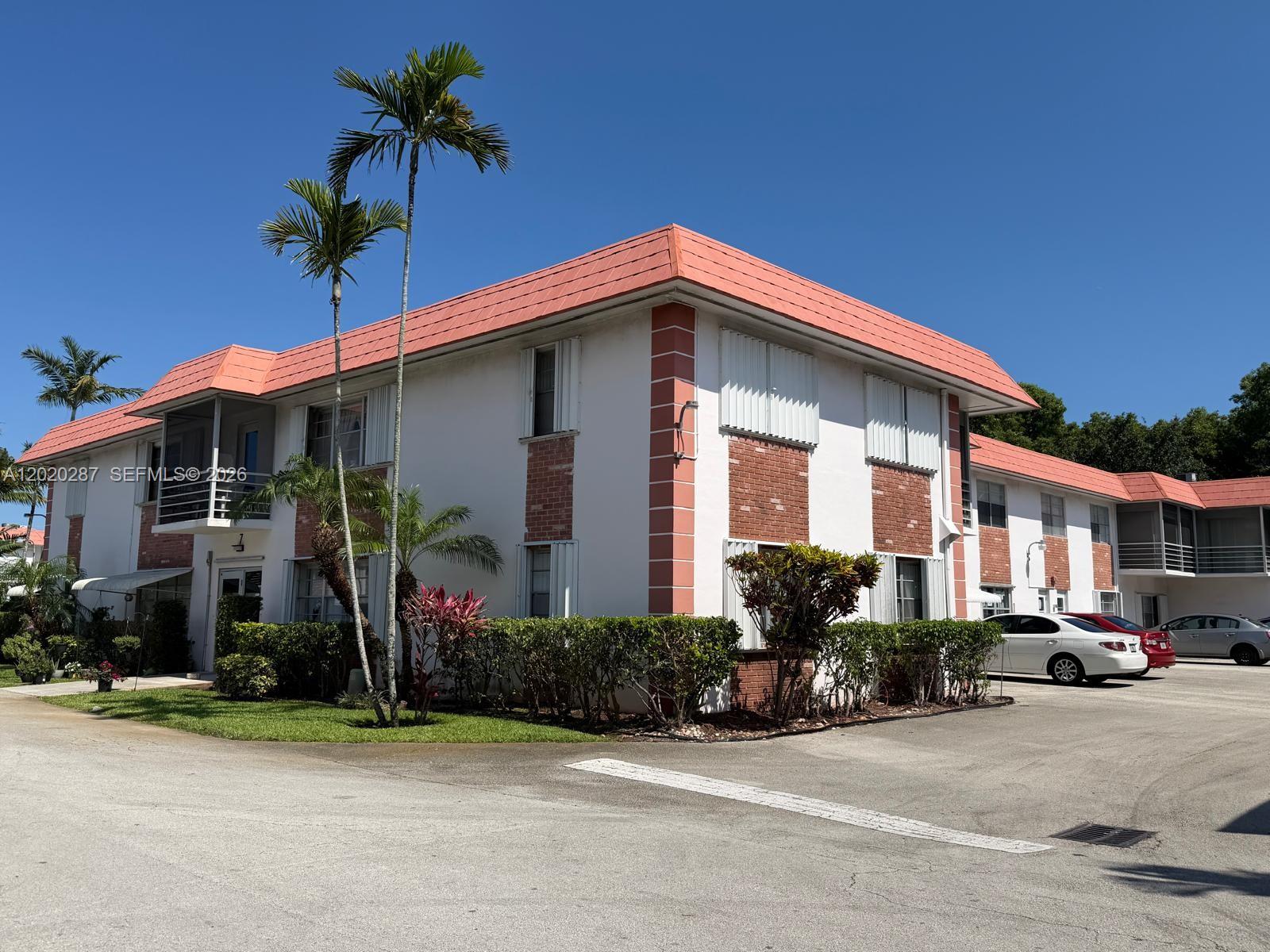 A two-story apartment building features white stucco walls, brick accents, and a salmon-colored roof — 3550 NW 8th Ave # 713, Pompano Beach FL 33064, POMPANO BEACH, FL