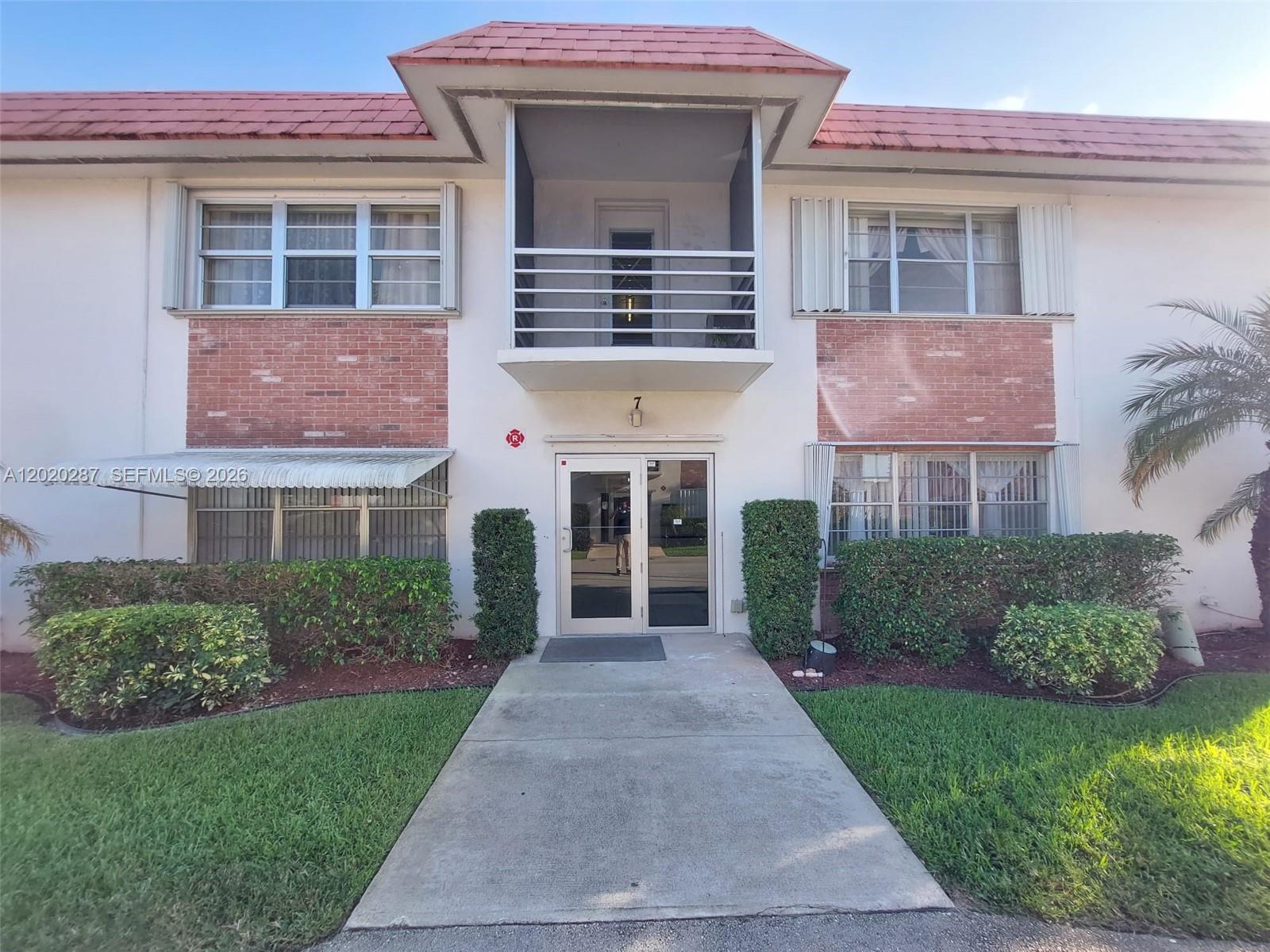 The exterior of a two-story apartment building features a central entrance and a second-floor balcony — 3550 NW 8th Ave # 713, Pompano Beach FL 33064, POMPANO BEACH, FL