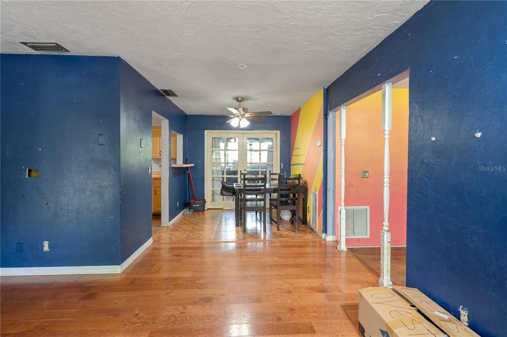 A dining area with wood floors, a ceiling fan, and a vibrant yellow-to-pink wall — 1717 NE 28TH AVENUE, GAINESVILLE, FL