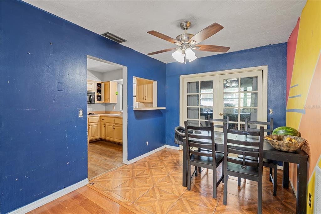 A dining room with blue walls, a ceiling fan, tile flooring, and a kitchen pass-through — 1717 NE 28TH AVENUE, GAINESVILLE, FL