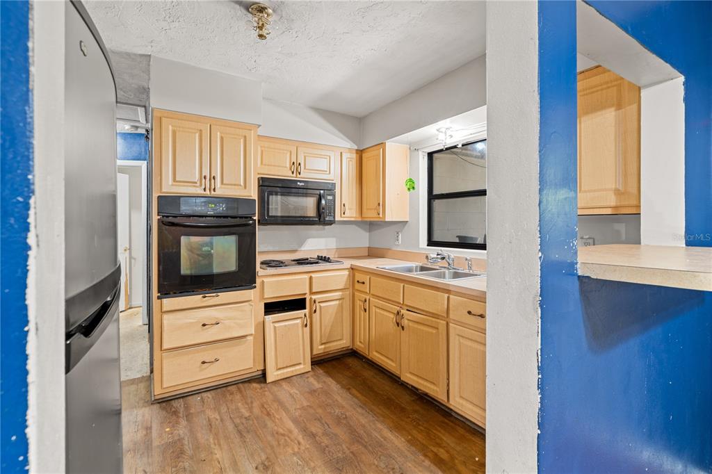 A kitchen features light wood cabinets, stainless steel appliances, and blue walls — 1717 NE 28TH AVENUE, GAINESVILLE, FL