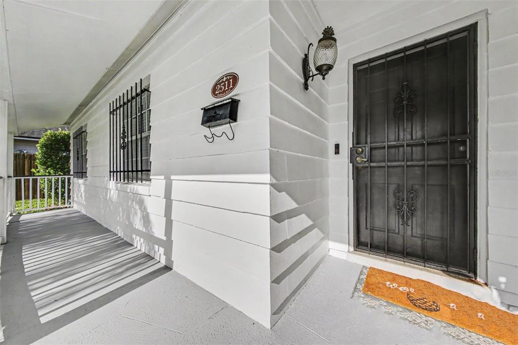 A white exterior wall with a black security door, mailbox, and a covered porch — 2511 EASTBROOK BOULEVARD, WINTER PARK, FL