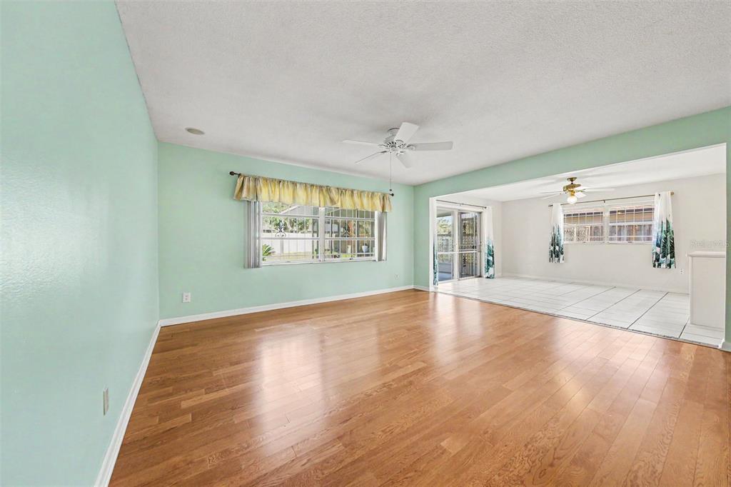 A living room with light green walls and hardwood floors opens into a tiled room — 2511 EASTBROOK BOULEVARD, WINTER PARK, FL