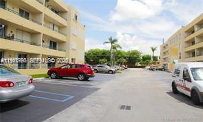 An outdoor parking lot is situated between two multi-story apartment buildings with palm trees — 8320 NW 8th St # 110, Miami FL 33126, MIAMI, FL