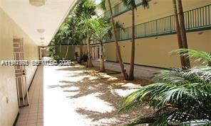 An outdoor walkway with palm trees leads toward a multi-story building with balconies — 8320 NW 8th St # 110, Miami FL 33126, MIAMI, FL