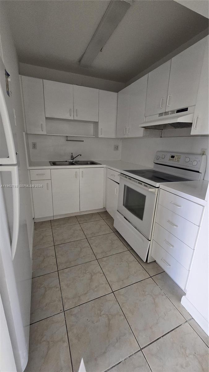 A small kitchen features white cabinets, white appliances, and light-colored tile flooring — 8320 NW 8th St # 110, Miami FL 33126, MIAMI, FL
