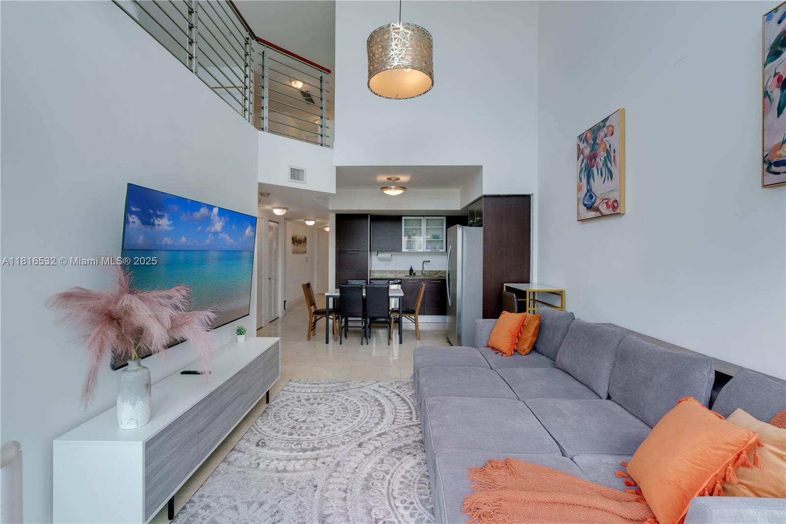A living room with high ceilings, a grey sectional sofa, and an open kitchen area — 41 SE 5th St # 2107, Miami FL 33131, MIAMI, FL