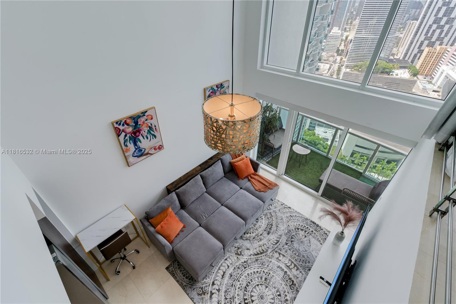 A high-angle view of a modern living room with a gray sectional and balcony — 41 SE 5th St # 2107, Miami FL 33131, MIAMI, FL