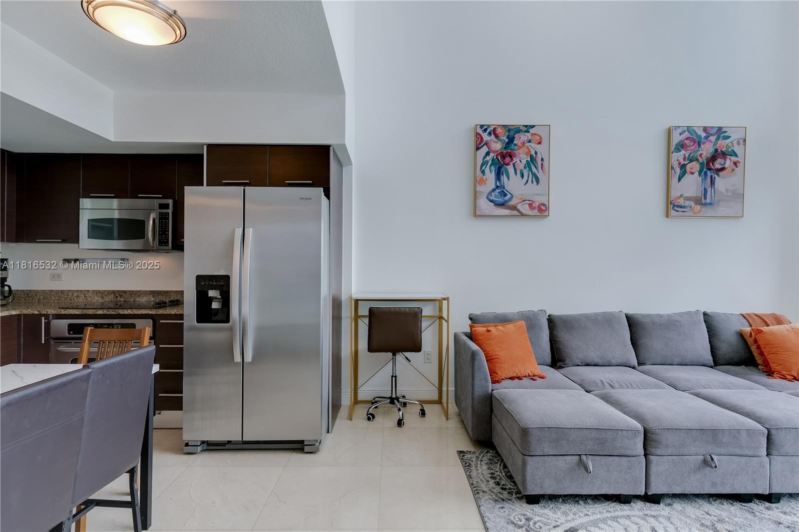 A kitchen with stainless steel appliances sits next to a living area with a gray sofa — 41 SE 5th St # 2107, Miami FL 33131, MIAMI, FL
