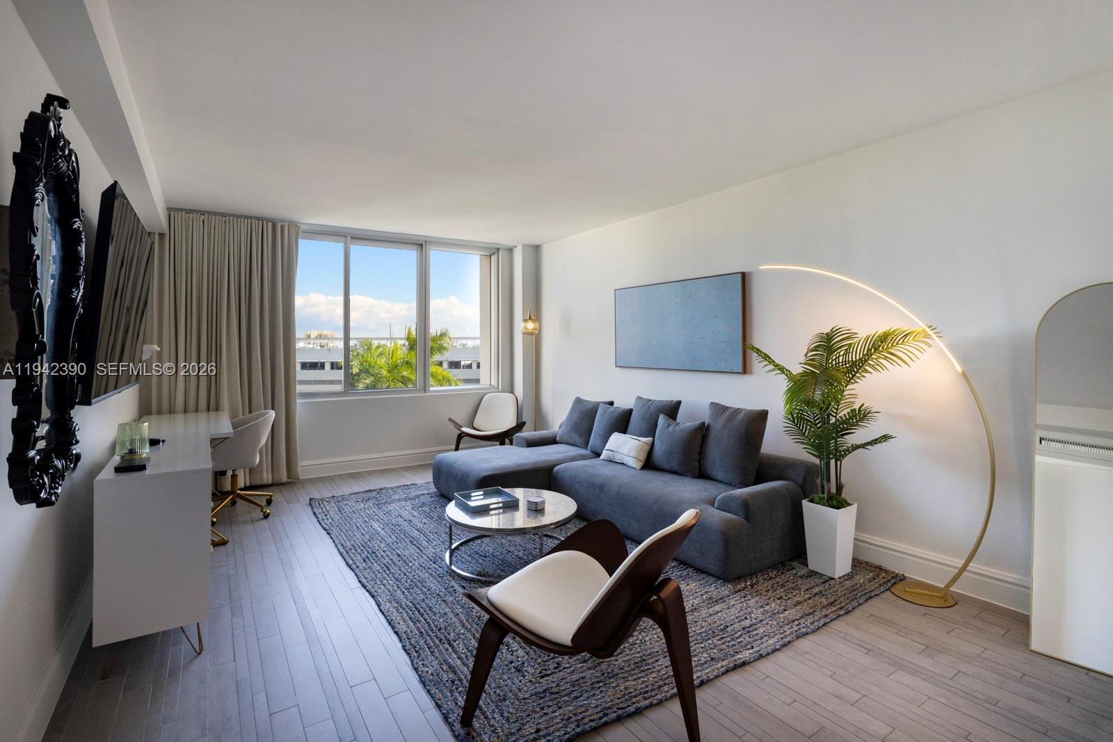 A modern living room features a gray sectional sofa, a blue area rug, and a desk — 1100 West Ave # 509, Miami Beach FL 33139, MIAMI BEACH, FL