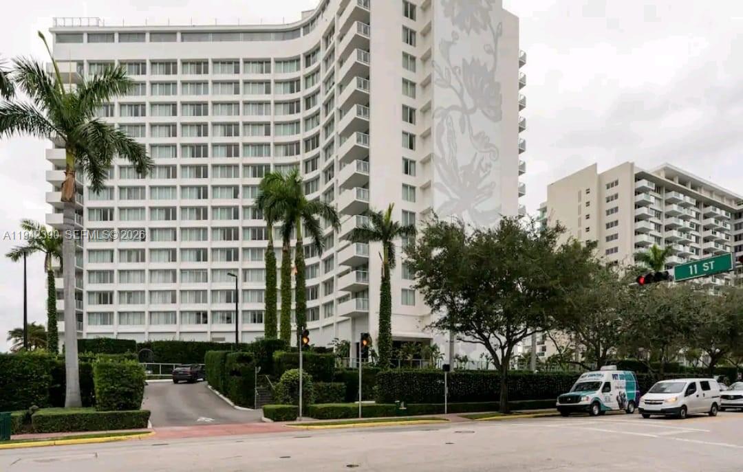 A tall, white multi-story hotel building with a floral mural stands behind palm trees — 1100 West Ave # 509, Miami Beach FL 33139, MIAMI BEACH, FL