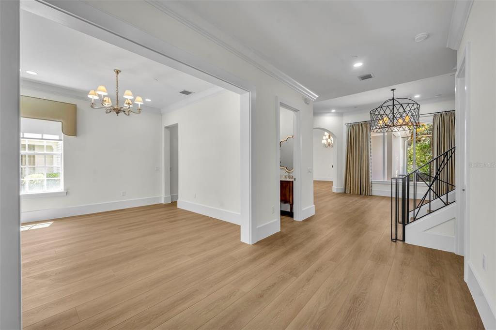 A bright, open-concept living area features light wood flooring, white walls, and two chandeliers — 4230 LOWER PARK ROAD, ORLANDO, FL