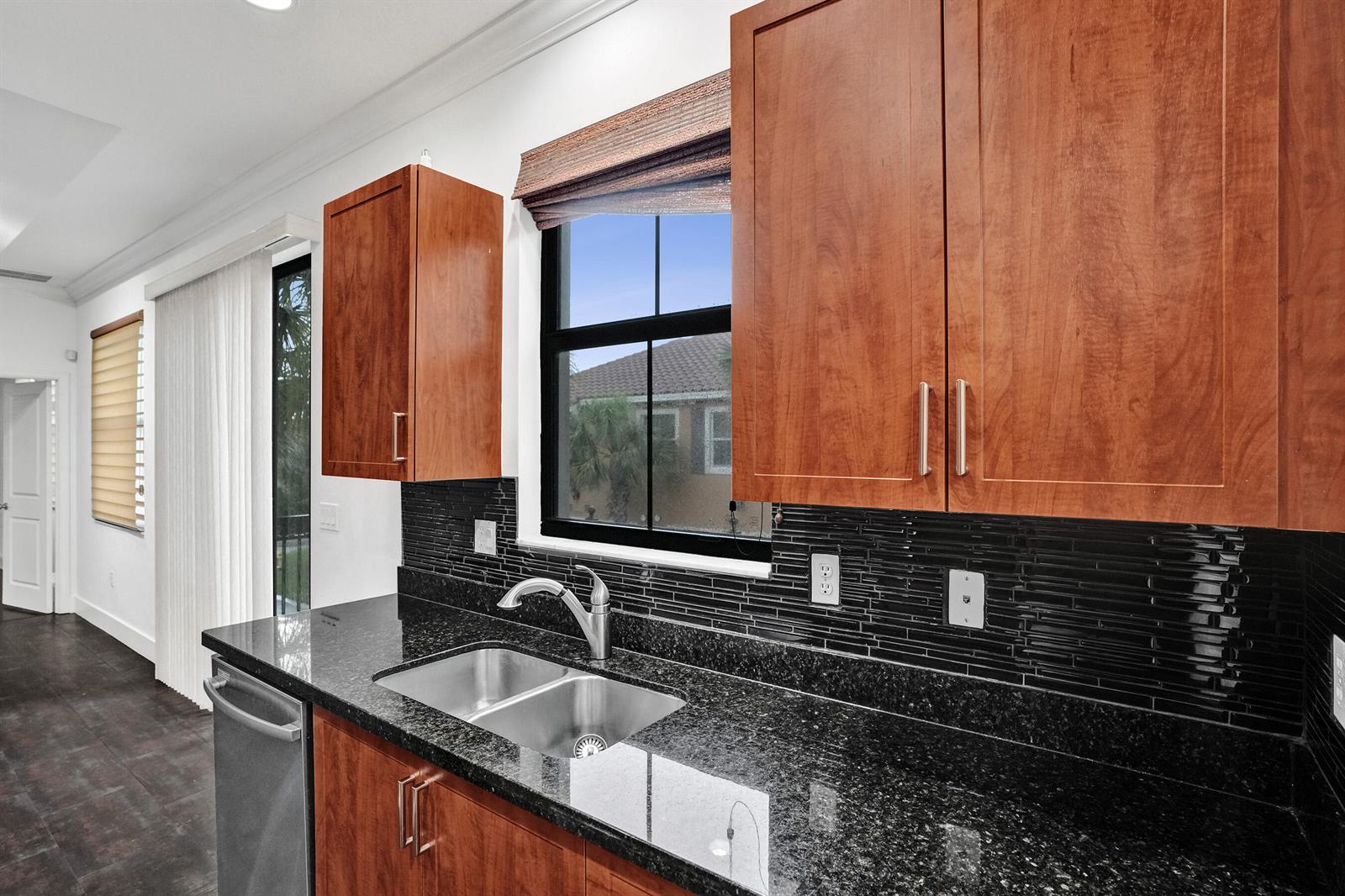 A kitchen features wood cabinets, black granite countertops, and a black tiled backsplash — 12662 NW 32nd Place, Sunrise FL 33323, SUNRISE, FL