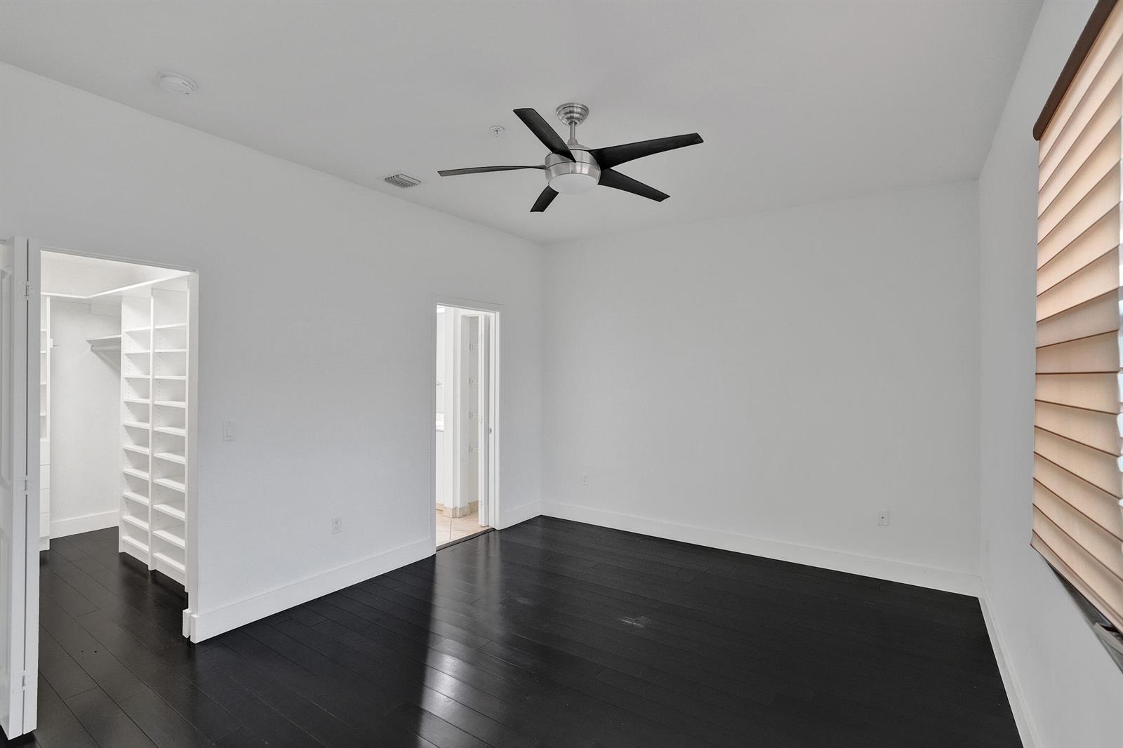An empty bedroom features dark hardwood floors, white walls, a ceiling fan, and a walk-in closet — 12662 NW 32nd Place, Sunrise FL 33323, SUNRISE, FL