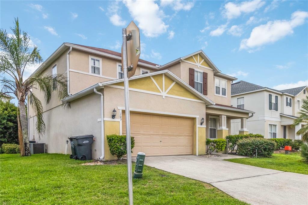 A two-story suburban house with a beige stucco exterior, a two-car garage, and a driveway — 103 BAY LEAF LANE, DAVENPORT, FL