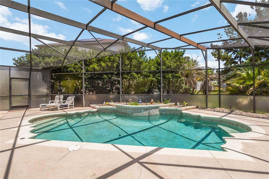 A screened-in swimming pool with a raised stone spa and patio area — 103 BAY LEAF LANE, DAVENPORT, FL