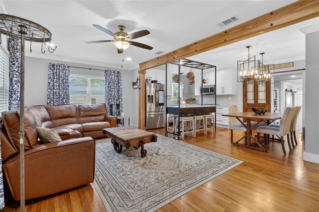 An open-concept living and dining area features hardwood floors, a leather sectional, and kitchen island — 1570 IMPERIAL AVENUE, BARTOW, FL