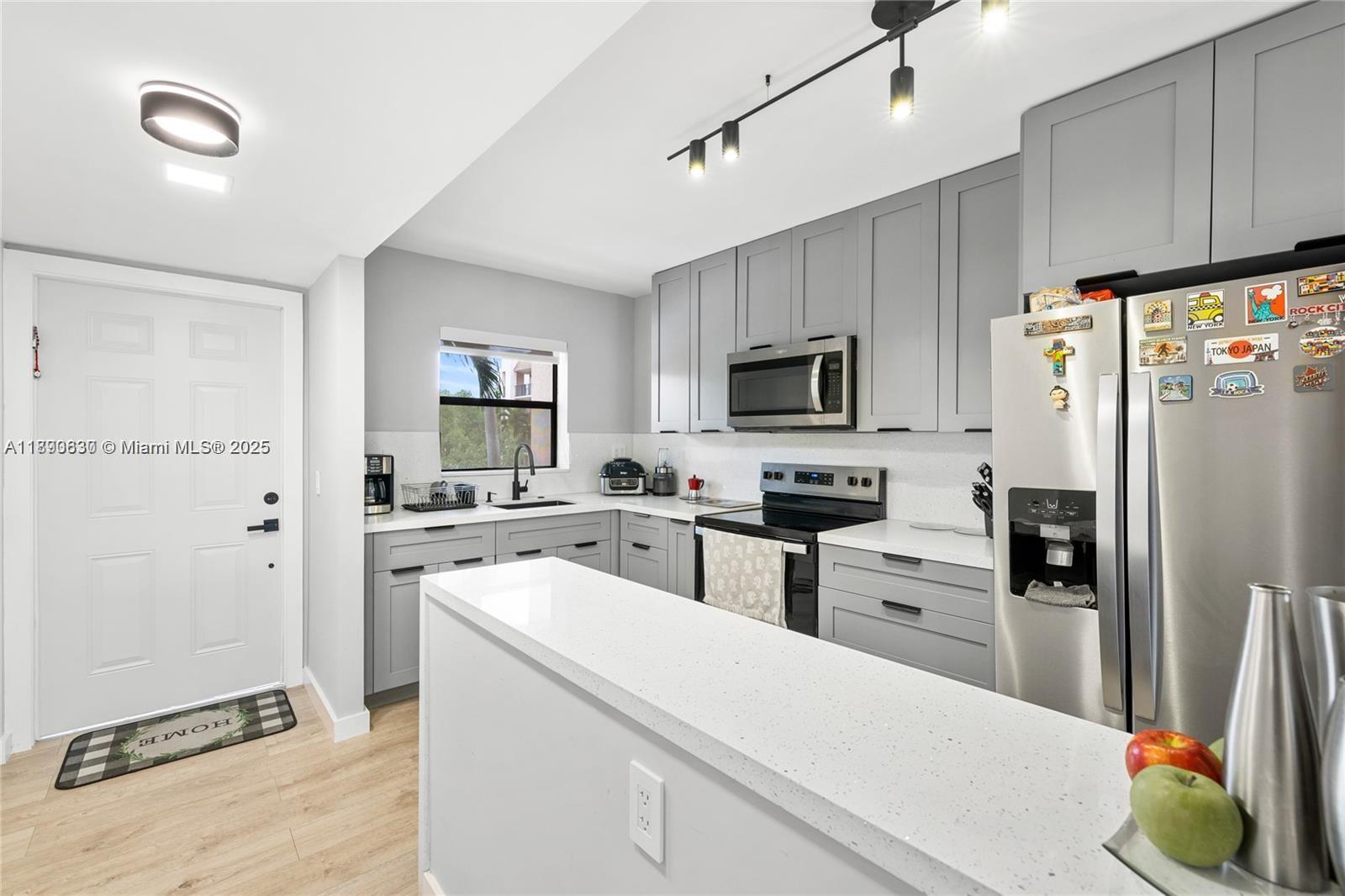 A kitchen features gray cabinets, white countertops, stainless steel appliances, and a breakfast bar — 10444 NW 30th Ct # 202, Sunrise FL 33322, SUNRISE, FL