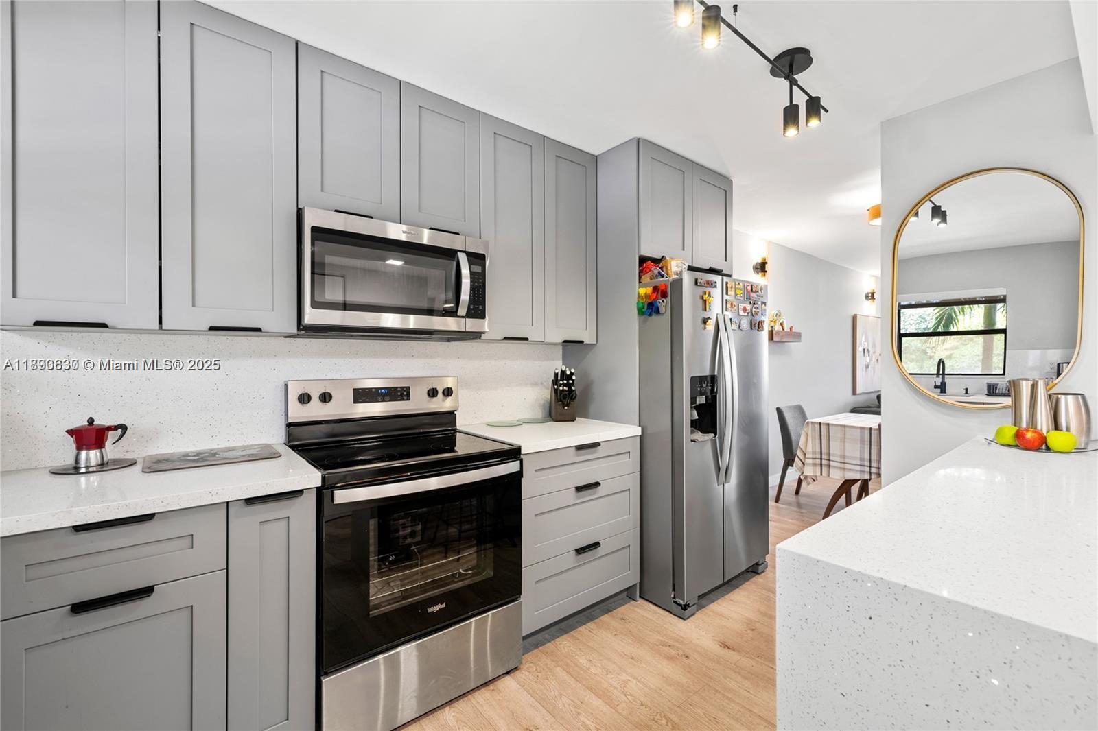 A modern kitchen features gray cabinets, stainless steel appliances, and white quartz countertops — 10444 NW 30th Ct # 202, Sunrise FL 33322, SUNRISE, FL