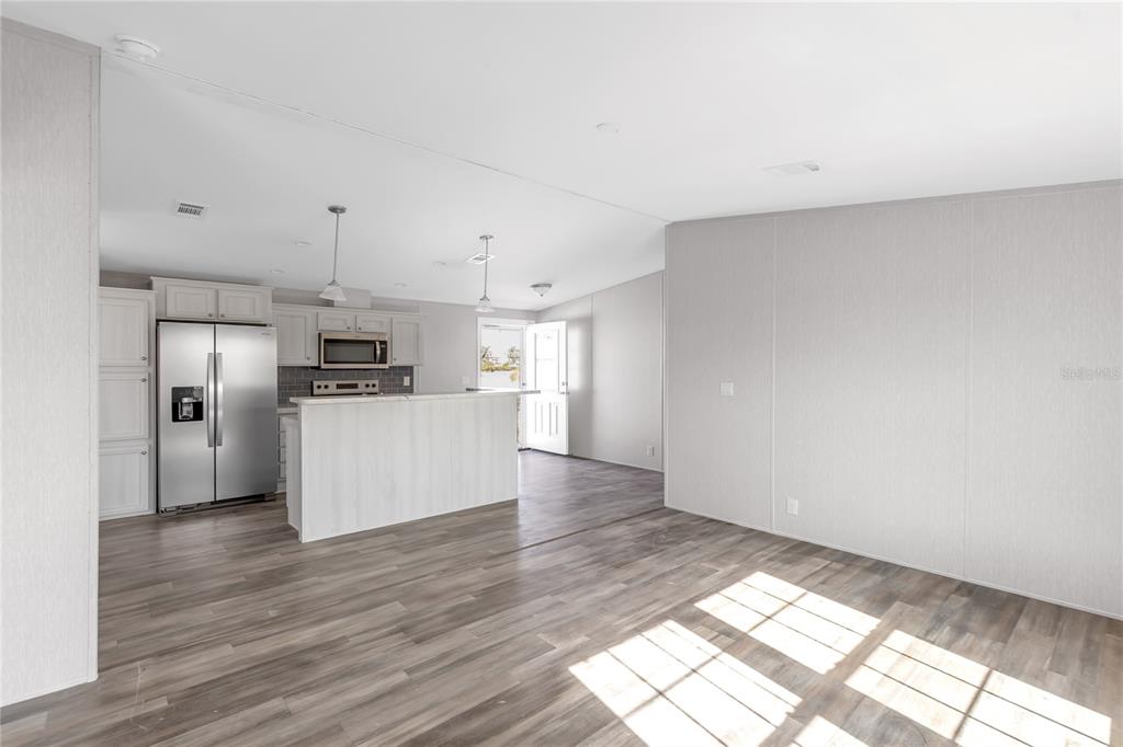 A kitchen with stainless steel appliances and a breakfast bar opens into a living area — 2107 PALMA SOLA BOULEVARD UNIT 13, BRADENTON, FL