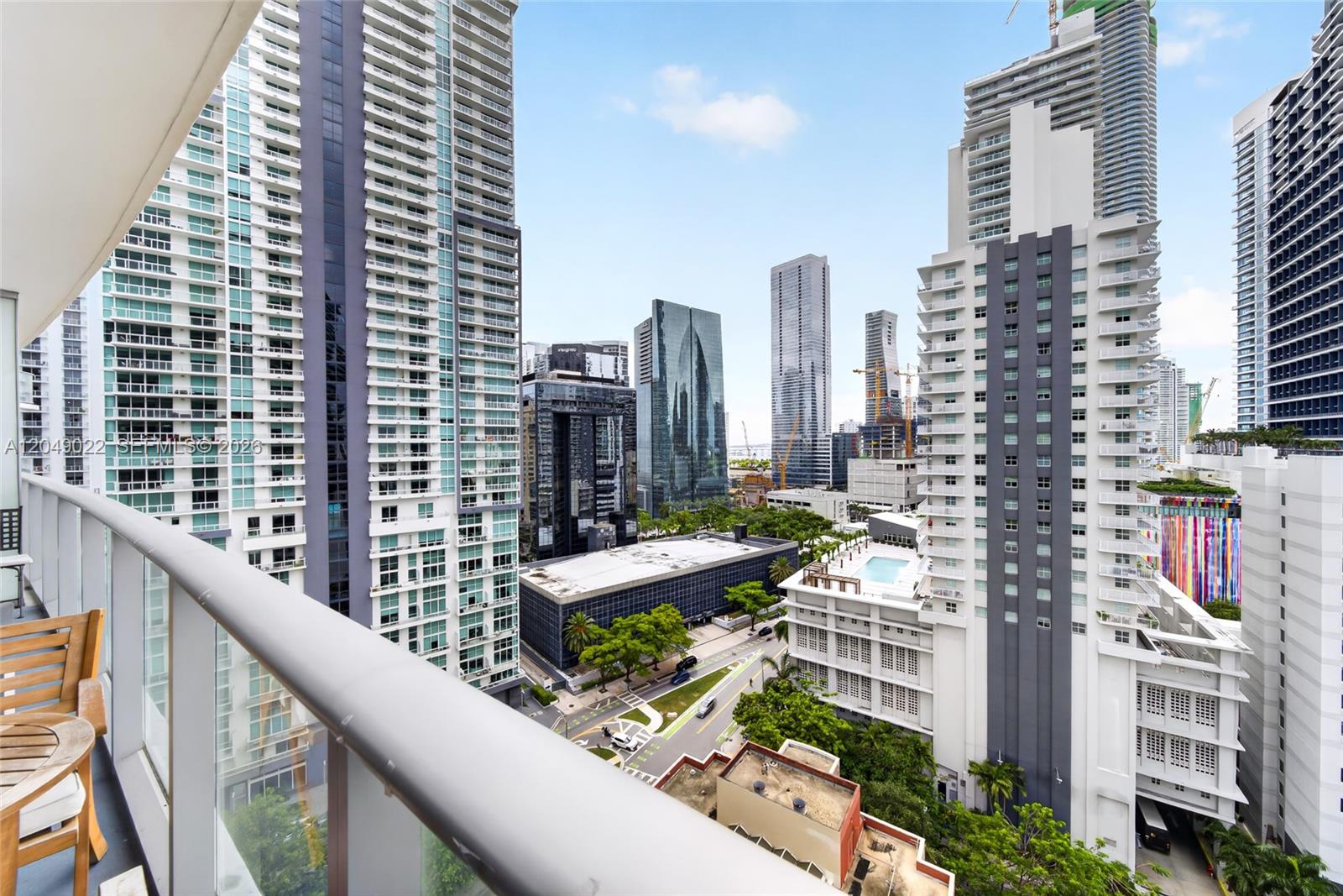 A high-rise balcony overlooks a dense urban cityscape with multiple modern skyscrapers and streets — 1100 S Miami Ave # 1603, Miami FL 33130, MIAMI, FL