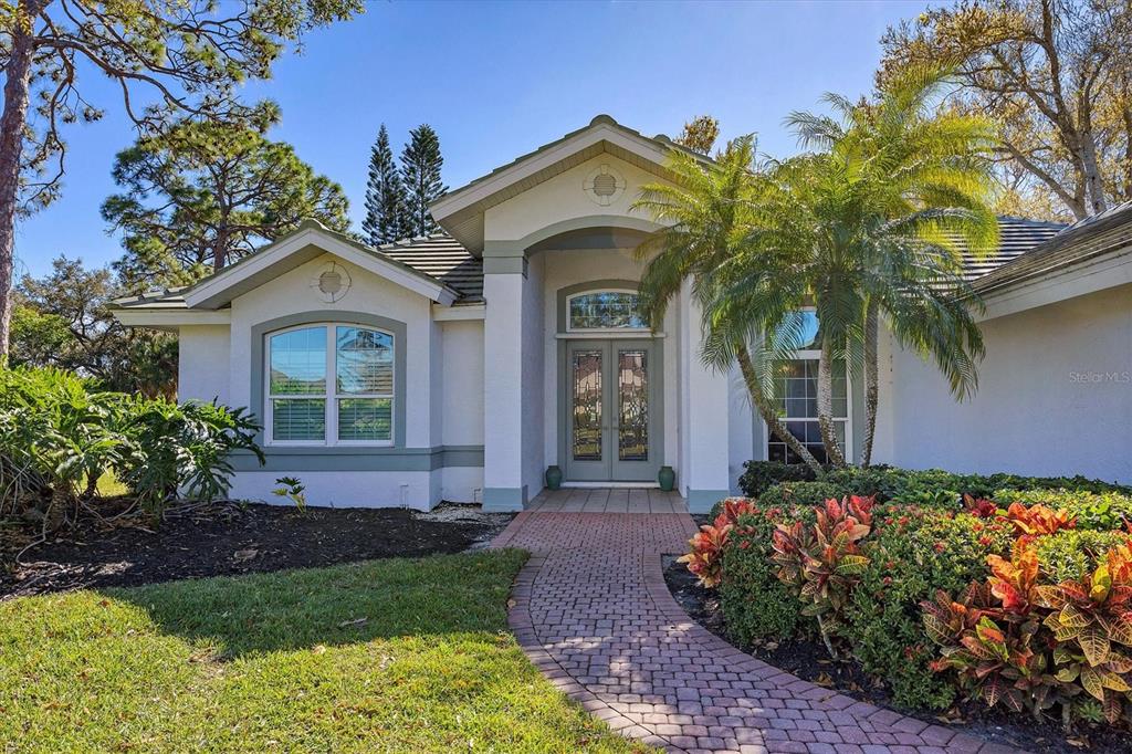 A single-story house with a brick walkway leading to a double-door entrance — 8684 WOODBRIAR DRIVE, SARASOTA, FL
