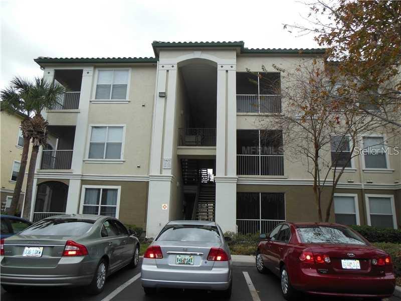 A three-story apartment building exterior with three cars parked in the foreground — 5807 LEGACY CRESCENT PLACE UNIT 201, RIVERVIEW, FL