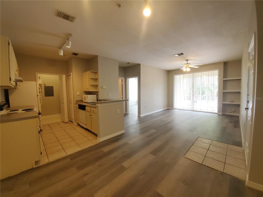 An open-concept living area features a kitchen with tile flooring and wood-look laminate flooring throughout — 5807 LEGACY CRESCENT PLACE UNIT 201, RIVERVIEW, FL