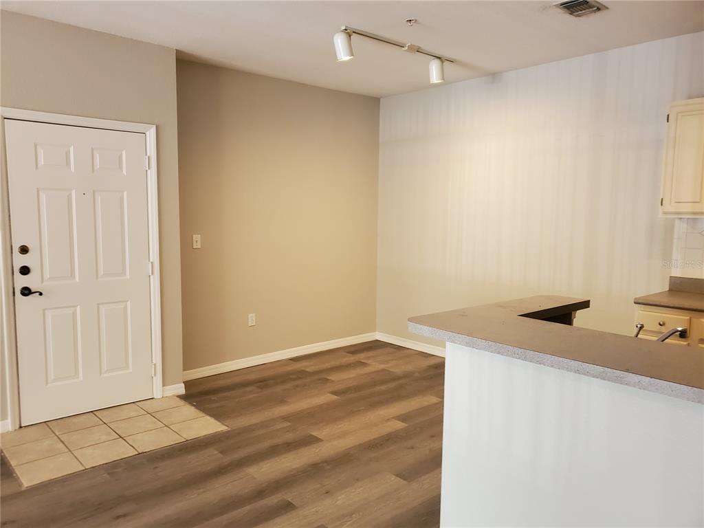 An interior view shows a room with wood-look flooring, a white door, and a kitchen counter — 5807 LEGACY CRESCENT PLACE UNIT 201, RIVERVIEW, FL