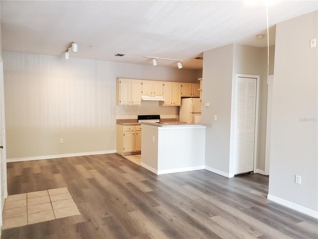 An open-concept kitchen with light-colored cabinets and a breakfast bar overlooks a living area — 5807 LEGACY CRESCENT PLACE UNIT 201, RIVERVIEW, FL