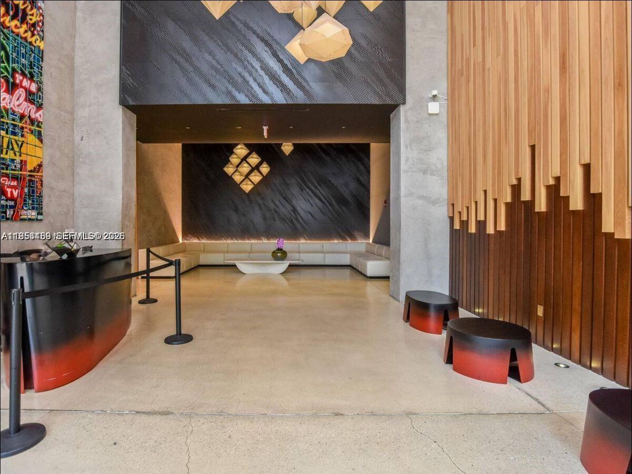A modern building lobby features a reception desk, lounge seating, and geometric wall lighting — 151 SE 1st St # 1207, Miami FL 33131, MIAMI, FL