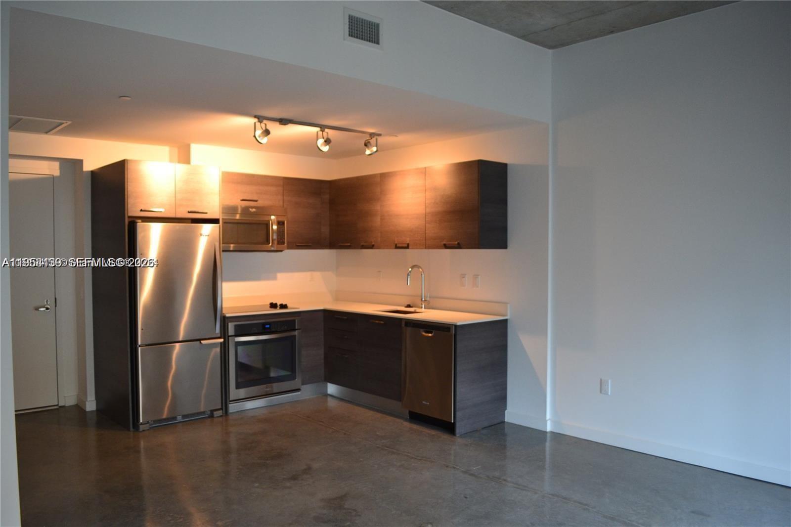 A modern kitchen features dark wood cabinets, stainless steel appliances, and polished concrete floors — 151 SE 1st St # 1207, Miami FL 33131, MIAMI, FL