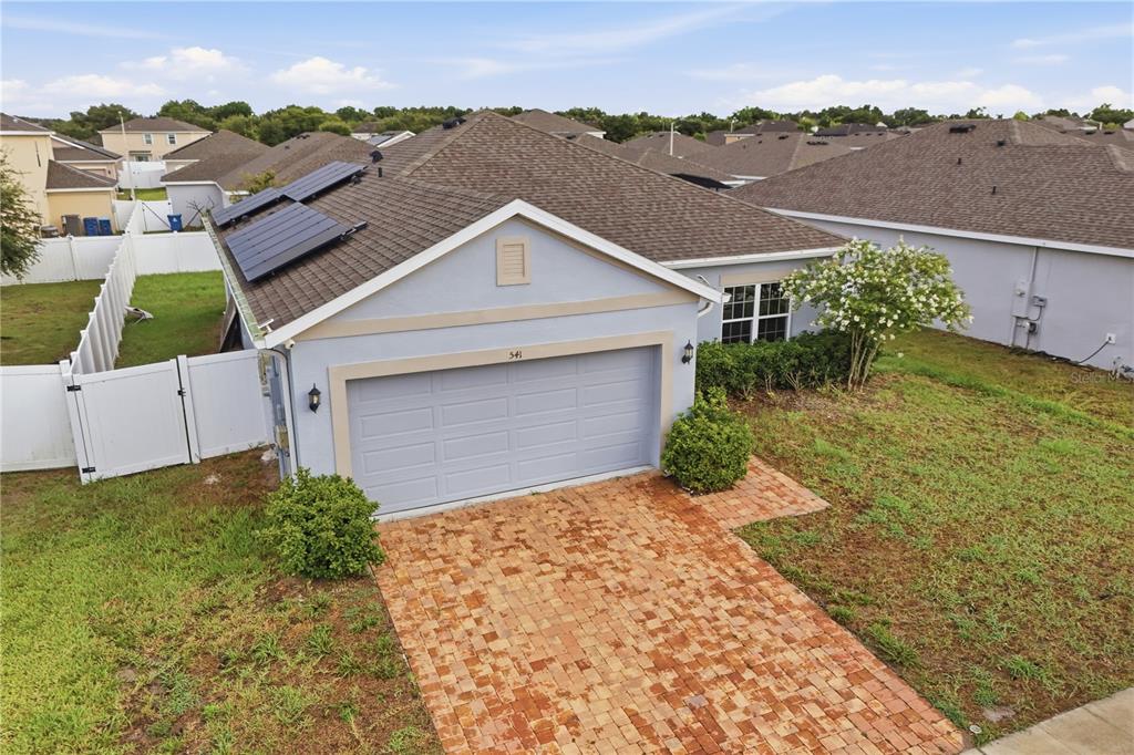 An aerial view of a single-story house with a brick driveway and solar panels — 541 WILDCAT LANE, DAVENPORT, FL