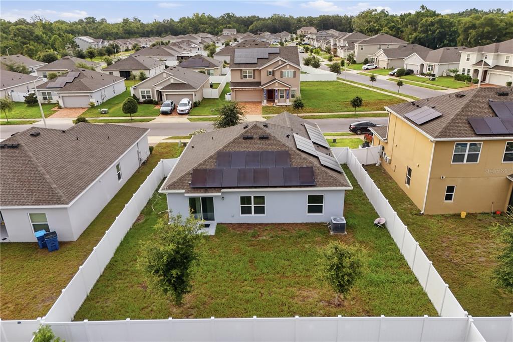 An aerial view shows a single-story house with solar panels and a fenced backyard — 541 WILDCAT LANE, DAVENPORT, FL
