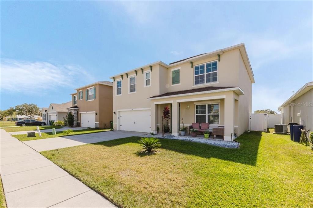 A two-story suburban house with a tan stucco exterior, a two-car garage, and a front porch — 344 ALEXZANDER WAY, WINTER HAVEN, FL