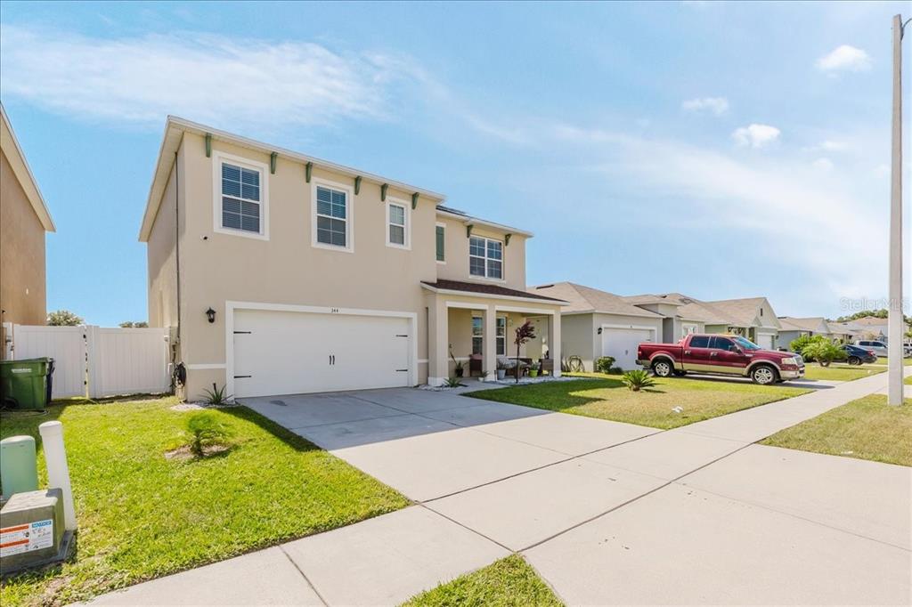A two-story suburban house with a beige stucco exterior, a two-car garage, and a driveway — 344 ALEXZANDER WAY, WINTER HAVEN, FL