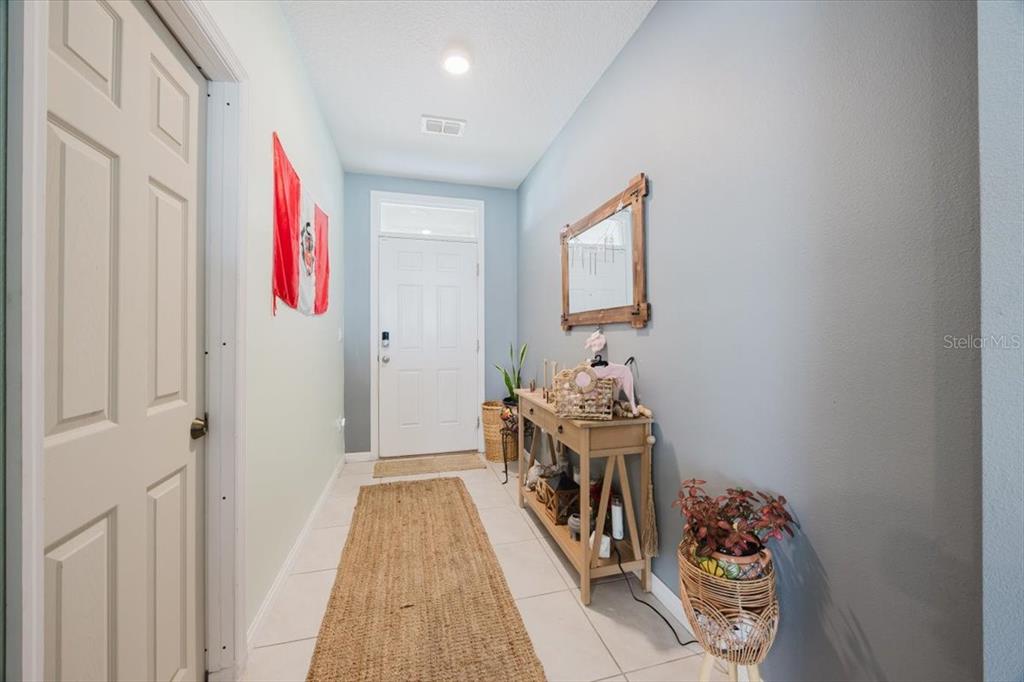 A hallway features light-colored tile flooring, a console table, a mirror, and a front door — 344 ALEXZANDER WAY, WINTER HAVEN, FL