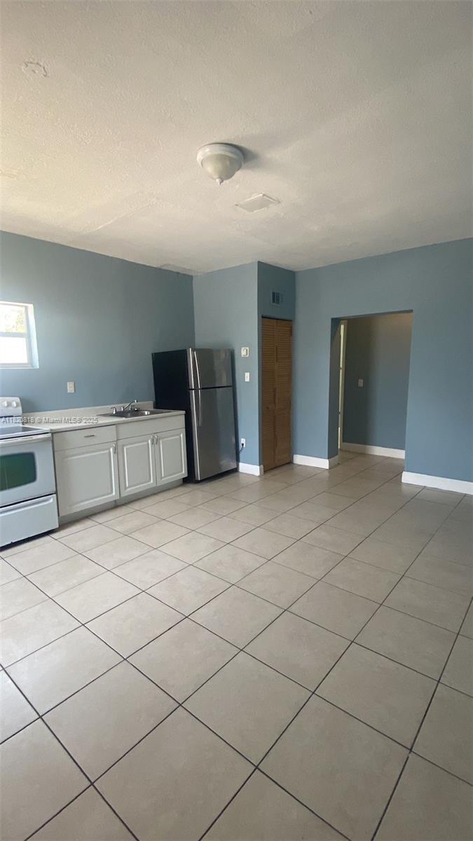 A kitchen with white cabinets, stainless steel appliances, and light-colored tile flooring — 2014 Funston St, Hollywood FL 33020, HOLLYWOOD, FL