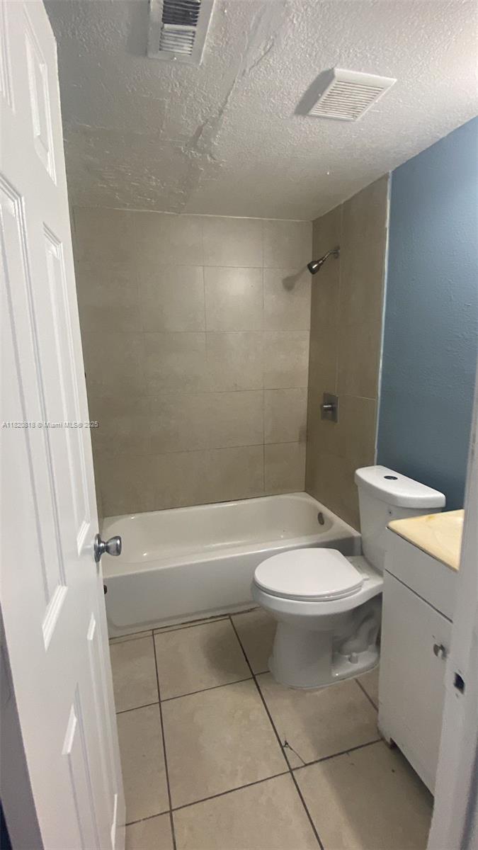 A small bathroom features a white bathtub, a toilet, and light-colored tile flooring and walls — 2014 Funston St, Hollywood FL 33020, HOLLYWOOD, FL