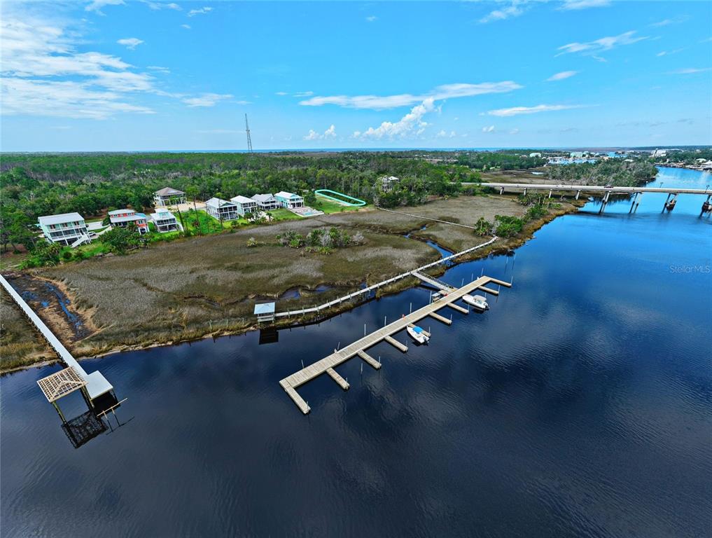 An aerial view shows a wooden dock extending into a river near coastal houses — 85 SW 279TH AVENUE, STEINHATCHEE, FL
