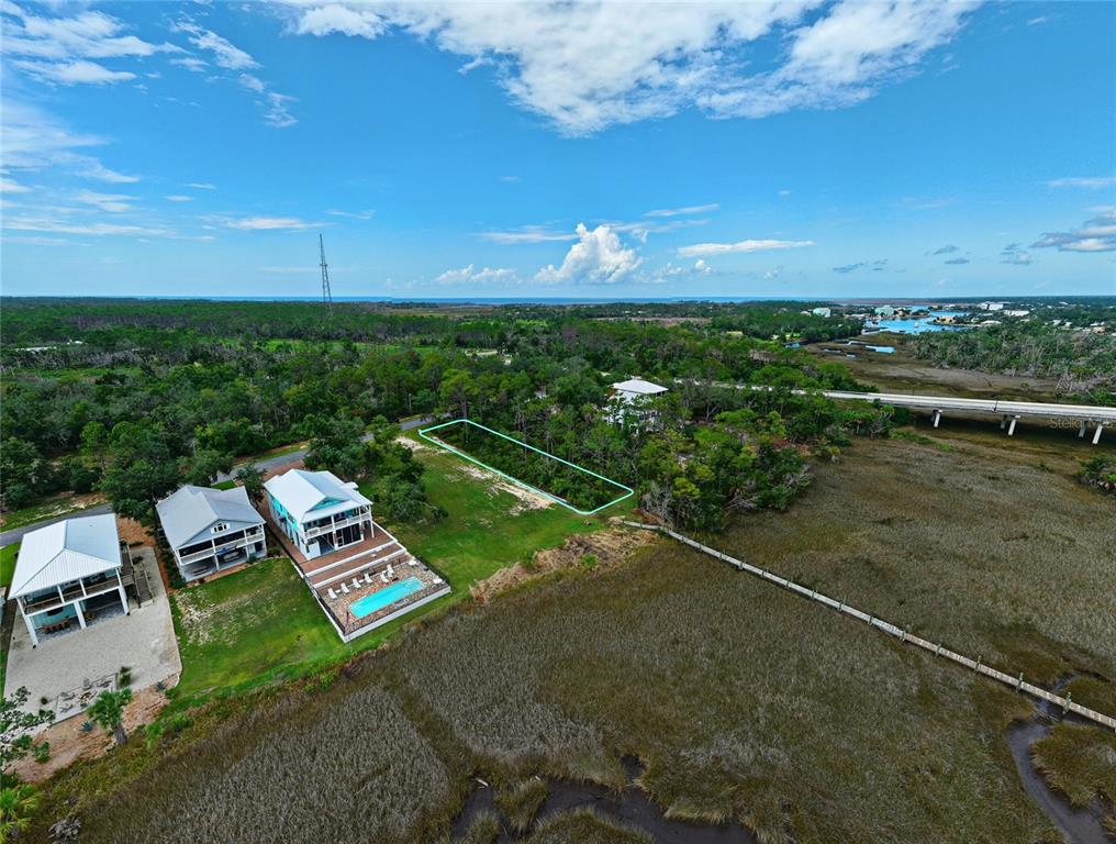 An aerial view shows a vacant rectangular lot outlined in blue next to coastal houses — 85 SW 279TH AVENUE, STEINHATCHEE, FL
