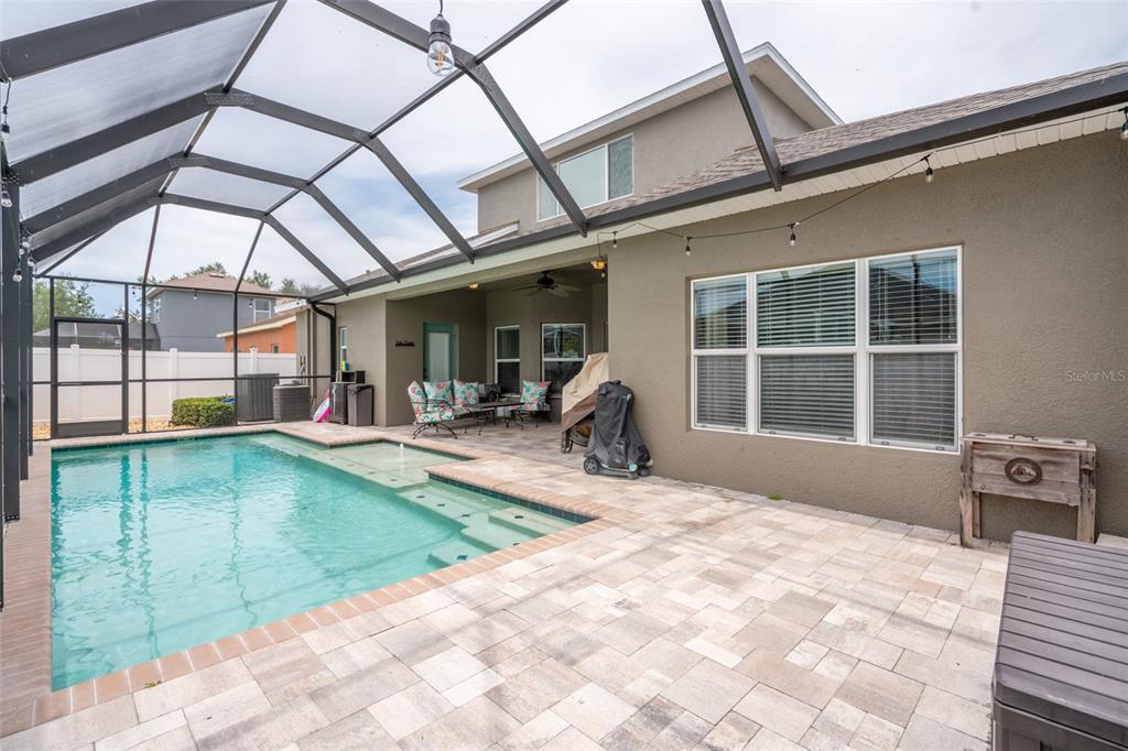 A screened-in patio features a swimming pool with a sun shelf and paver decking — 1809 BONITA BLUFF COURT, RUSKIN, FL